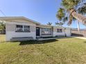 Inviting home exterior showcasing a lush green lawn, complemented by a swaying palm tree for a relaxed, tropical feel at 444 Driftwood Rd, Venice, FL 34293