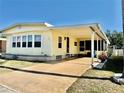 Charming manufactured home with bright yellow siding, covered carport, and well-maintained landscaping at 5619 Bayshore Rd # 421, Palmetto, FL 34221