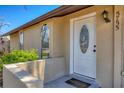 Close-up of the home's entrance featuring a white front door with decorative glass and manicured landscaping at 5755 Oxalis Rd, Venice, FL 34293