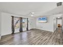 Open-concept living room featuring hardwood floors, a ceiling fan, and a mounted flat-screen television at 5755 Oxalis Rd, Venice, FL 34293