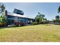 Backyard featuring a large screened in porch, a spacious lawn, and mature tropical landscaping at 610 Alligator Dr, Venice, FL 34293