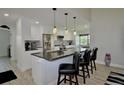 Modern kitchen featuring a granite island with seating, stainless steel appliances, and elegant pendant lighting at 611 Paget Dr, Venice, FL 34293