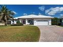 Charming single-story home with a well-manicured lawn and a brick driveway leading to a two-car garage at 617 Bonito Ave, Nokomis, FL 34275
