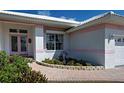 Inviting front entrance with a brick walkway, lush landscaping, and a stylish pink-framed double door at 617 Bonito Ave, Nokomis, FL 34275