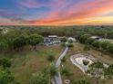 Panoramic aerial shot showcasing the home, pond, and surrounding trees under a vibrant sunset sky at 6824 283Rd E St, Myakka City, FL 34251