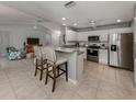 Open kitchen with stainless appliances, a breakfast bar, tile floors, and seamless access to the living area at 791 Cumberland Rd, Venice, FL 34293