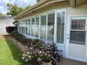Bright enclosed patio with large windows and well maintained yard with vibrant pink flowers at 810 Anchorage Ln, Palm Harbor, FL 34685