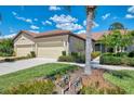 Home exterior showcasing a tan two-car garage, driveway, and tropical landscaping at 11186 Batello Dr, Venice, FL 34292