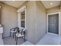 Inviting front porch with a seating area including two chairs and a table, next to front door and window at 11455 Fort Lauderdale Pl, Venice, FL 34293