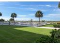 Inviting pool area surrounded by lush green grass, palm trees, and a glimpse of the ocean at 1150 Tarpon Center Dr # 3G 307, Venice, FL 34285
