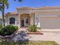 Inviting facade with arched entryway, wood door, tile roof, and brick paver walkway at 11610 Dancing River Dr, Venice, FL 34292