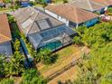 Aerial view of a backyard with a screened pool, surrounded by lush greenery and a fence at 11711 Alessandro Ln, Venice, FL 34293