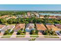 Birds eye view of a neighborhood featuring a beautiful home, lush trees, and a serene lake at 11711 Alessandro Ln, Venice, FL 34293