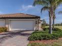Exterior showcases an attached garage, brick driveway, and well-maintained landscaping with palm trees at 12515 Felice Dr, Venice, FL 34293