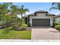 Beautiful single-story home featuring a two-car garage, tile roof, brick paver driveway, and lush tropical landscaping at 12897 Oriago St, Venice, FL 34293