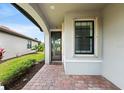 Inviting front porch with brick flooring, leads to a modern home with well-maintained landscaping and a window at 12897 Oriago St, Venice, FL 34293
