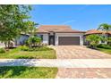 Single-Gathering home with barrel tile roof, paver driveway, and manicured landscaping at 13202 Borrego St, Venice, FL 34293