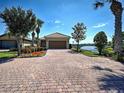 Inviting home featuring a brick driveway and colorful landscaping, complemented by a tranquil lake view at 19240 Isadora St, Venice, FL 34293