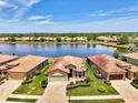 Scenic aerial shot of a home by a lake with lush landscaping and a terracotta tile roof at 20246 Pezzana Dr, Venice, FL 34292