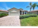 Charming single-story home with a brick driveway, palm tree, and manicured green lawn at 20246 Pezzana Dr, Venice, FL 34292