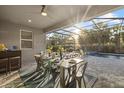 Covered outdoor dining area with a table set for a meal, overlooking the pool and lush landscaping at 20591 Ovid Ln, Venice, FL 34293