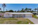 Charming single-story home with a metal roof, lush landscaping, and an attached garage at 2108 Lee Ln, Sarasota, FL 34231