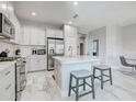 Bright kitchen featuring white cabinets, stainless steel appliances, island with seating, and tile flooring at 220 Sarezzo Cir, Nokomis, FL 34275