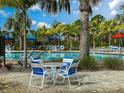 Community pool with blue umbrellas and lawn chairs in a tropical landscaped setting with palm trees at 220 Sarezzo Cir, Nokomis, FL 34275