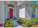 Close up on a red front door, showing the landscaping and architectural detail at 2318 Harrier Way, Nokomis, FL 34275