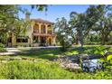 Two-story home features balconies, a tile roof, a green lawn, and mature trees at 2750 Gocio Road Ext, Sarasota, FL 34235