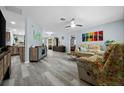 Bright living room features wood-look floors, light blue walls, ceiling fan, and modern furnishings at 3355 Roslyn Rd, Venice, FL 34293