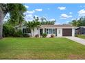 Inviting single-story home with a large front yard, mature landscaping, and an attached garage at 348 Dorchester Dr, Venice, FL 34293