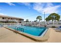 Community pool area with clear blue water, surrounded by a white fence, landscaping and lounge chairs at 360 Base E Ave # 413, Venice, FL 34285
