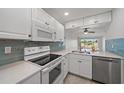 Bright kitchen features white cabinets, modern appliances, tile backsplash and breakfast bar overlooking the dining area at 406 Cerromar N Cir # 128, Venice, FL 34293