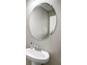 Close-up of a pedestal sink in the bathroom with a stylish faucet and oval mirror at 4523 Birdsong Dr, Palmetto, FL 34221