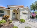 Charming home featuring a tile roof, arched entry, two-car garage, and well-maintained landscaping with an American flag at 4885 Tamarack Trl, Venice, FL 34293