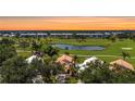 Scenic aerial view of the community, showcasing lush green golf course and community buildings at sunset at 542 Clubside Cir # 20, Venice, FL 34293