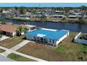 Waterfront home showcasing a blue roof, lush landscaping, and canal access at 6422 Otis Rd, North Port, FL 34287