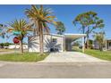 Street view of home with carport, mature palm trees, and fresh landscaping at 6803 Amoko Ct, North Port, FL 34287