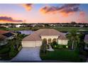 Beautiful home with a well-manicured lawn, a tile roof, and a three-car garage, set against a scenic sunset at 872 Macaw Cir, Venice, FL 34285