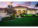 Inviting home exterior with arched entryway, lush landscaping, and a well-maintained lawn, showcasing curb appeal at 872 Macaw Cir, Venice, FL 34285