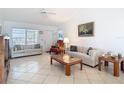 Bright living room featuring tile flooring, a ceiling fan, neutral-colored sofas, and a large window for natural light at 985 Everest Rd, Venice, FL 34293