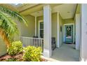 Inviting front porch with neutral decor, a glass front door, and serene landscaping for a relaxing welcome at 12478 Sagewood Dr, Venice, FL 34293