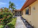 Inviting home with stone walkway, tropical plants, and a screened entrance at 1320 Whispering Ln, Venice, FL 34285