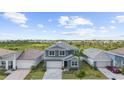 Aerial view of a two-story home with a gray facade, featuring a well-kept lawn and brick-paved driveway at 18001 Grand Prosperity Dr, Venice, FL 34293