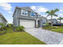 Two-story home with a brick-paved driveway leading to a two-car garage, complemented by a well-maintained lawn and landscaping at 18001 Grand Prosperity Dr, Venice, FL 34293