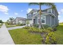 Two-story home showcasing a well-kept lawn, complemented by a brick-paved driveway and lush landscaping at 18001 Grand Prosperity Dr, Venice, FL 34293