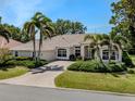Charming home with a brick driveway and well-manicured landscaping, featuring palm trees and a tile roof at 2022 Calusa Lakes Blvd, Nokomis, FL 34275