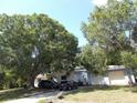 A single story home with mature trees in the front yard and a detached garage at 2682 Yamada Ln, North Port, FL 34286