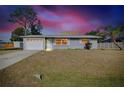 Charming single-story home with a well-manicured lawn and attached garage during sunset at 2980 Siesta Dr, Venice, FL 34293